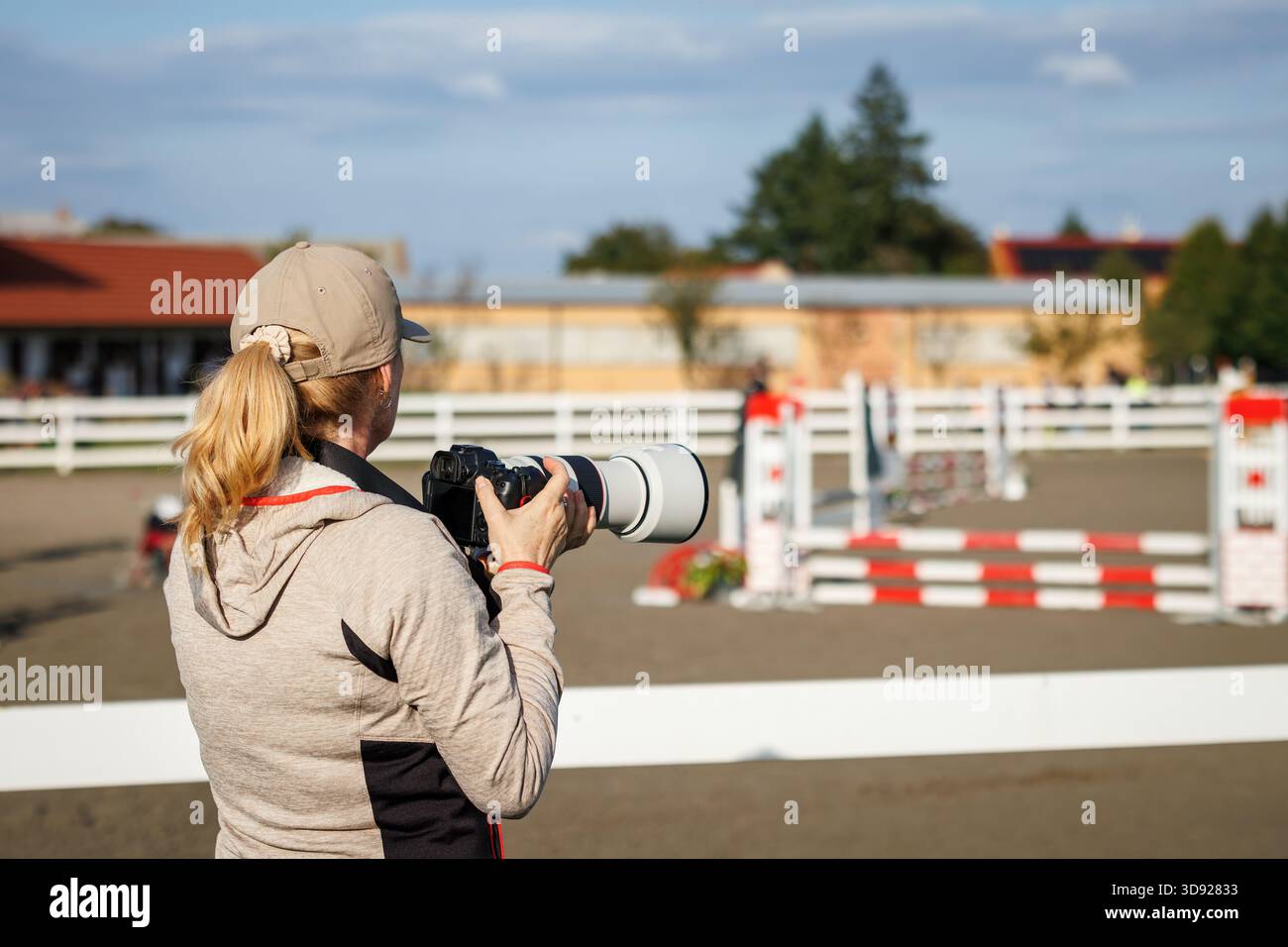 Fotografa donna con fotocamera che fotografa una gara equestre. Giornalista sportivo professionista Foto Stock