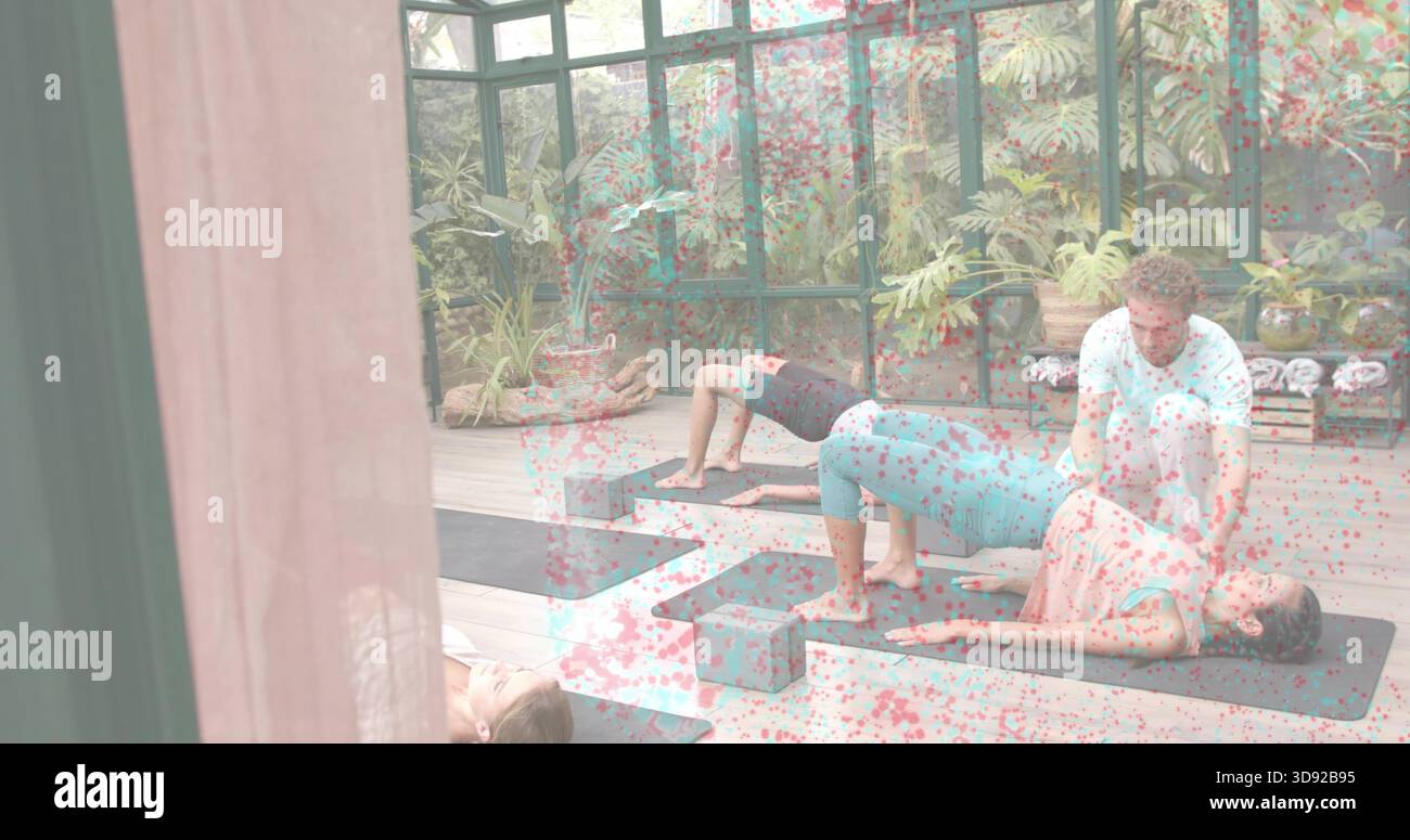 Assistere l'istruttore nella regolazione dello studente che indossa la parte superiore rosa in uno studio di vetro, utilizzando blocchi di schiuma e pesi Foto Stock