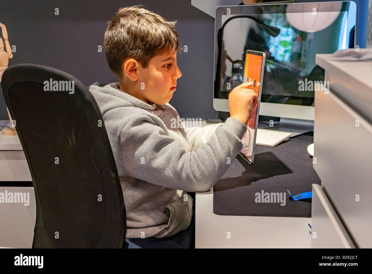 Il ragazzo triste che usa un tablet in camera da letto si preoccupava dei rischi legati a Internet e ai social media, come il cybebyllying e il phishing Foto Stock