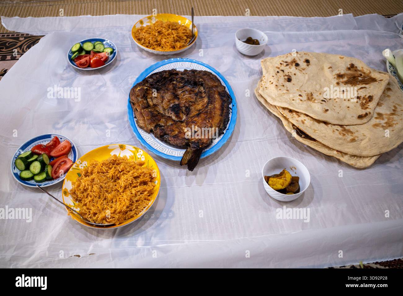Nasiriyah, Iraq - 20 novembre 2025: Tradizionale festa del pesce Masgouf e del riso servita all'interno di un fango di canna Foto Stock