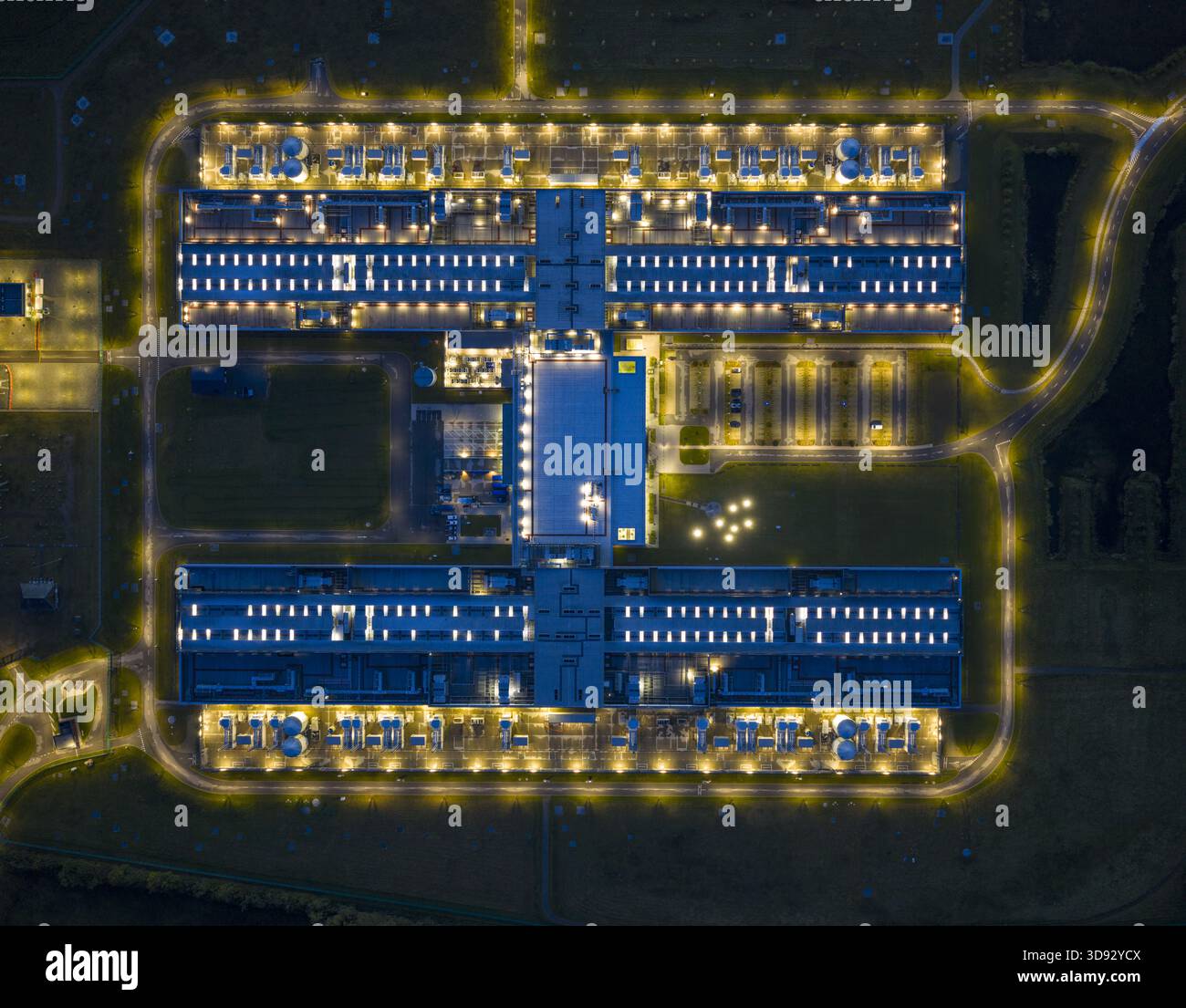 Veduta aerea di un complesso di edifici simmetrici luminosi illuminati in mezzo al paesaggio scuro, un faro di luce e precisione architettonica, Odense, S. Foto Stock