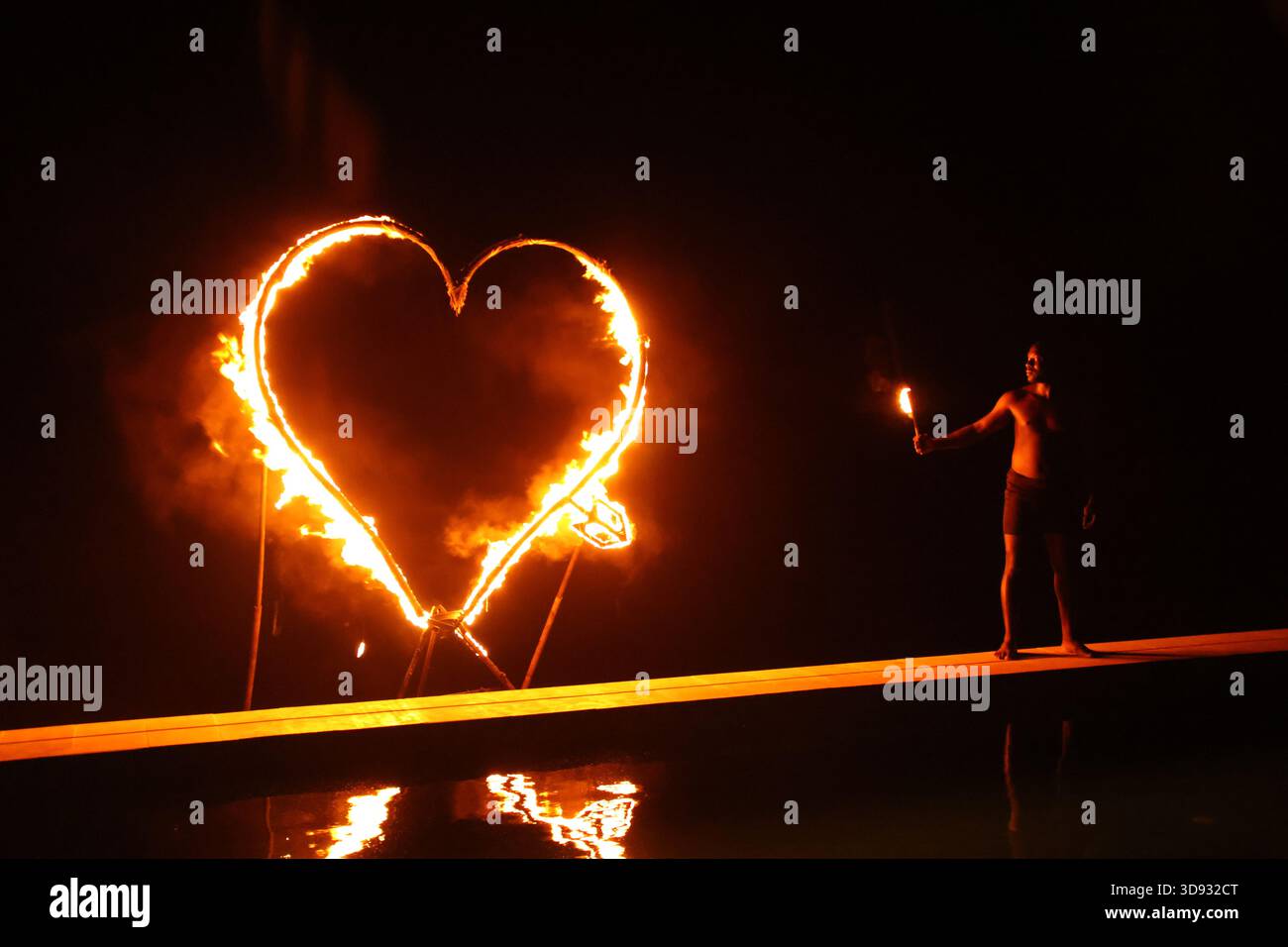 Nella luce soffusa, l'arte del fuoco illumina la notte buia del deserto di Agafay con il suo spettacolo artistico del cuore. Foto Stock