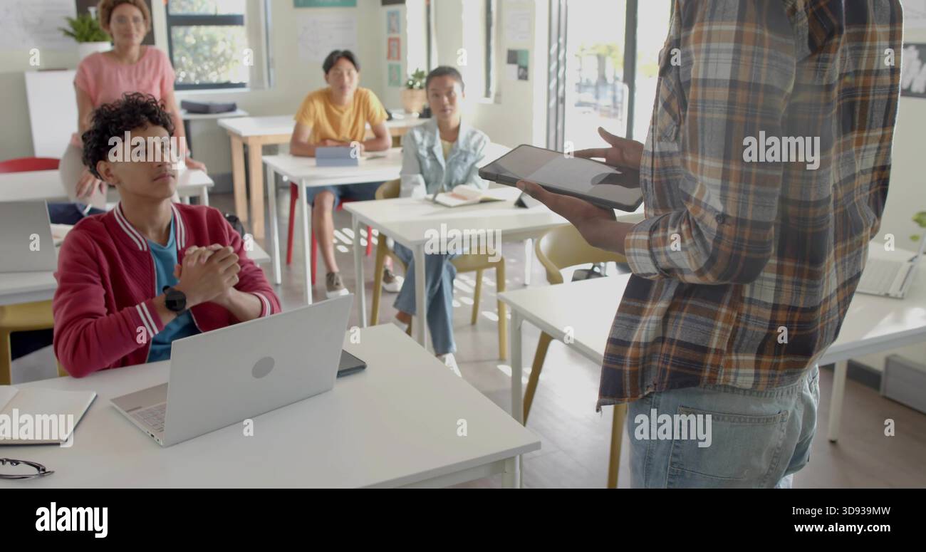 Presentazione dell'istruttore in camicia a quadri, jeans con tablet rivolti agli studenti in classe, spazio copia Foto Stock