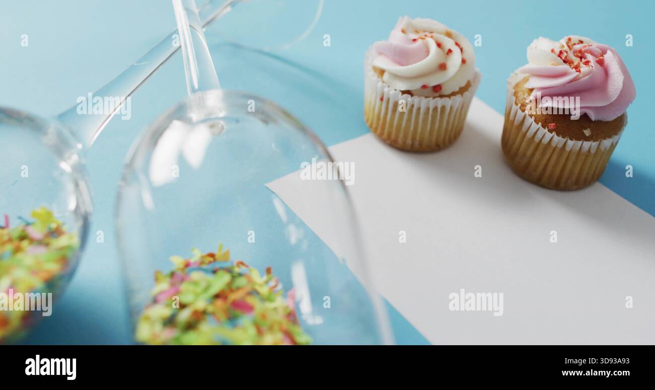 Mostra due cupcake smerigliati su una superficie blu pallido, spruzzi di bicchieri, spazio per copiare Foto Stock