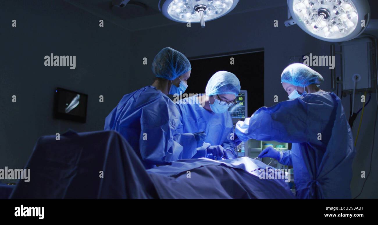 Gruppo operatorio chirurgico che esegue interventi chirurgici in SALA OPERATORIA, indossando abiti e maschere blu, con strumenti Foto Stock