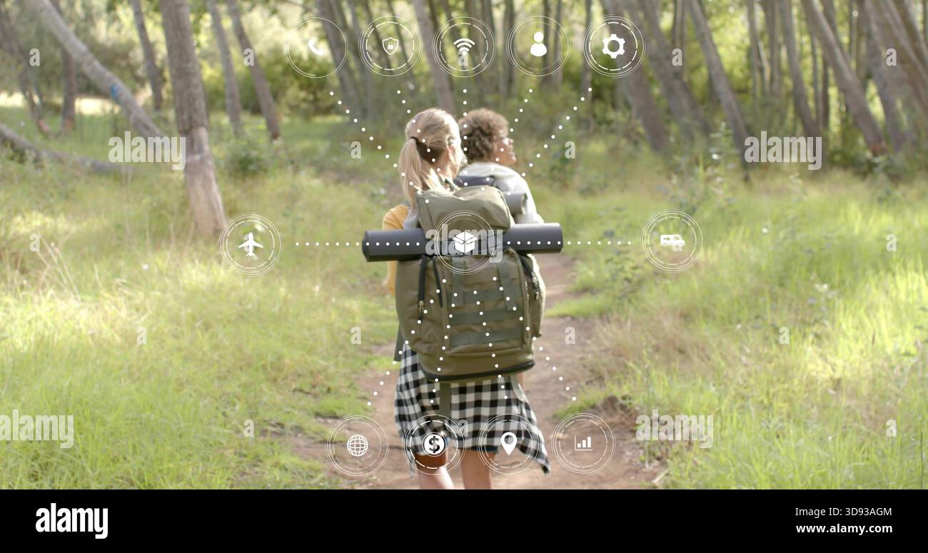 Escursionisti in cima gialla e gonna a scacchi lungo il sentiero della foresta, con icone AR sullo zaino Foto Stock
