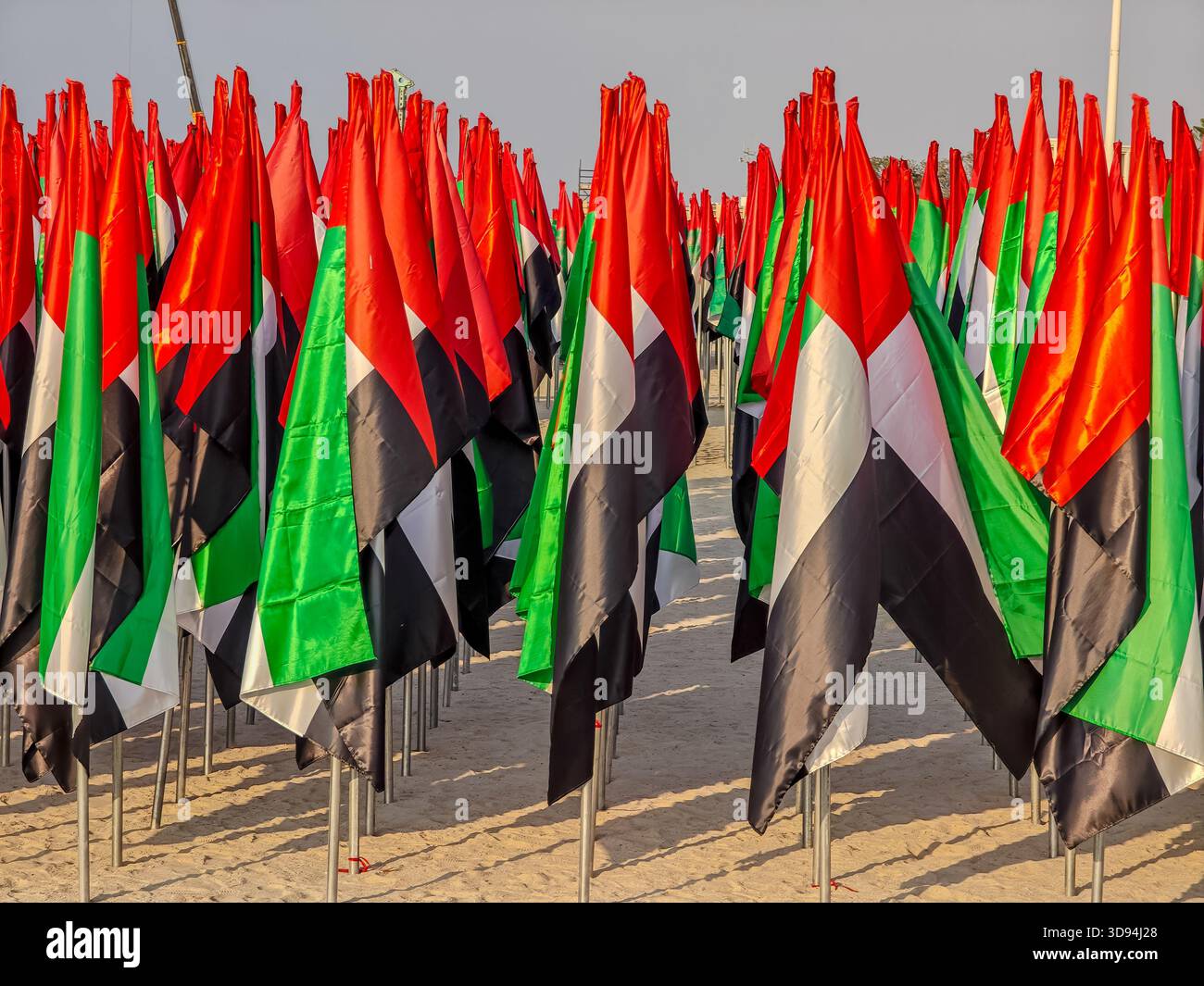 Migliaia di bandiere degli Emirati Arabi Uniti piantate nella sabbia a Jumeirah Beach formano una vibrante mostra patriottica. Attributo giorno nazionale Foto Stock