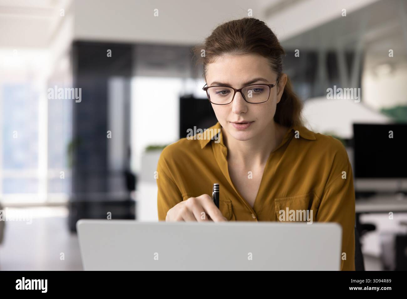 Giovane professionista caucasico concentrato in occhiali che lavora al notebook Foto Stock