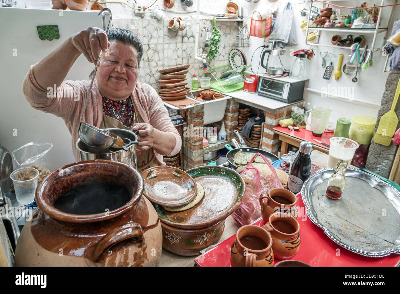 Città del Messico, Messico, Xochimilco, Dalia Restaurant Cafe, donna ispanica latinoamericana che prepara cucina tradizionale, mestolo pentola di argilla, cucina Foto Stock