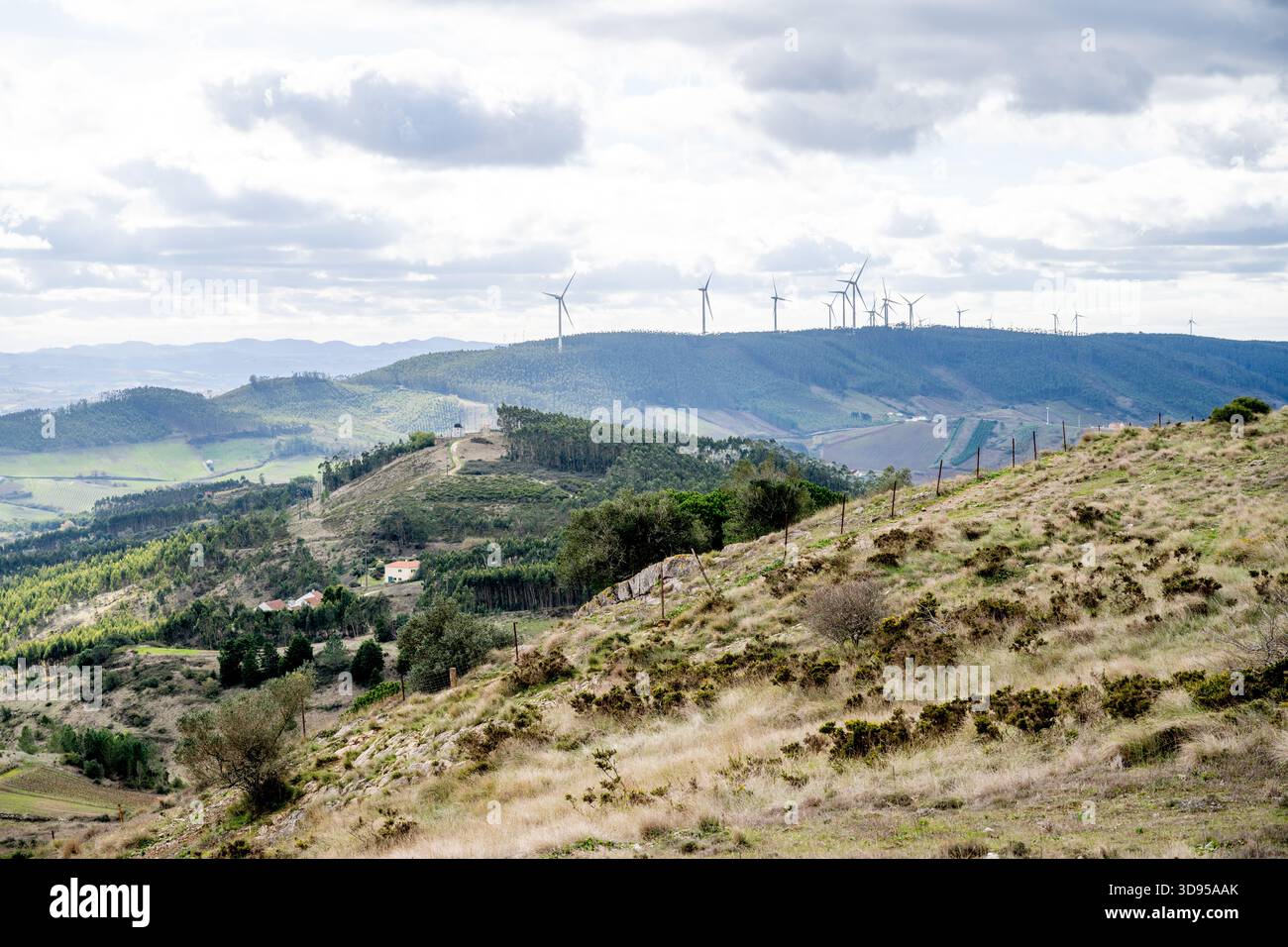 Alenquer Portogallo novembre 29 2025. Le turbine eoliche si innalzano sopra pendii boscosi e terreni agricoli attraverso la valle di Montejunto sotto nuvole stratificate Foto Stock