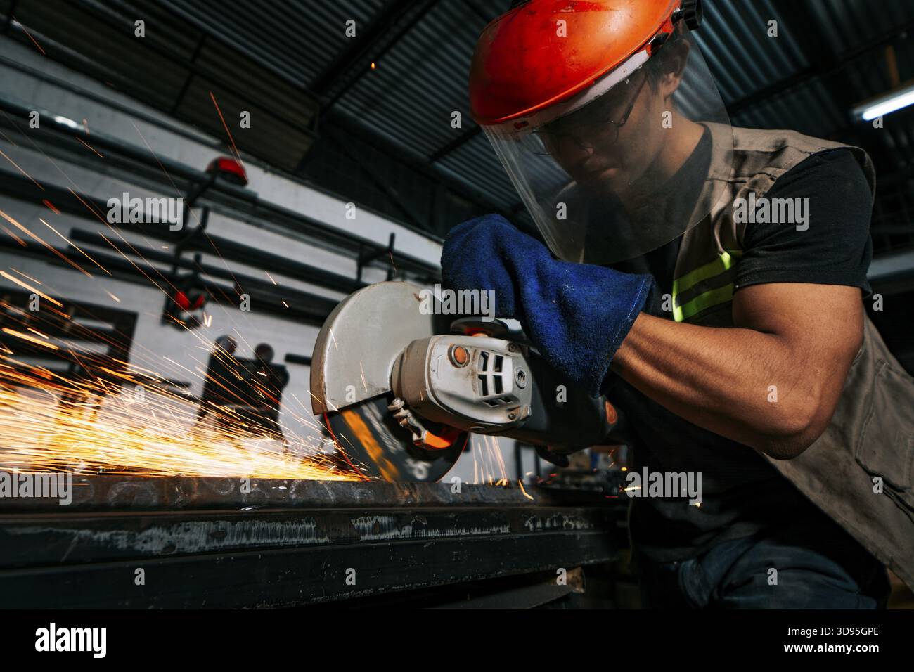 Professionista della metallurgia che lavora con una smerigliatrice in officina. Uomo che lavora con una smerigliatrice angolare su un banco di lavoro in officina Foto Stock