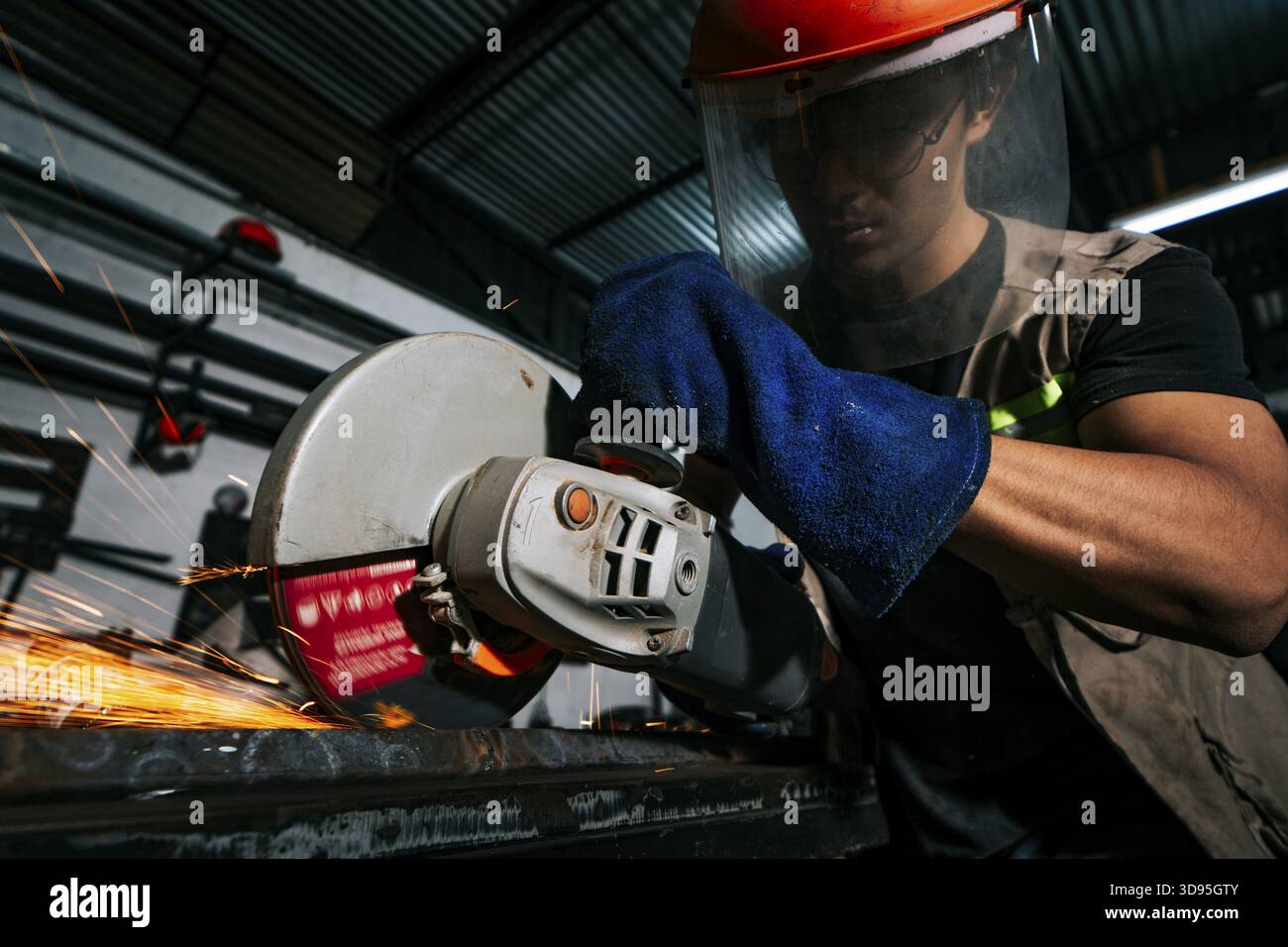 Uomo che lavora con una smerigliatrice angolare su un banco di lavoro in officina. Professionista della metallurgia che lavora con una smerigliatrice in officina Foto Stock