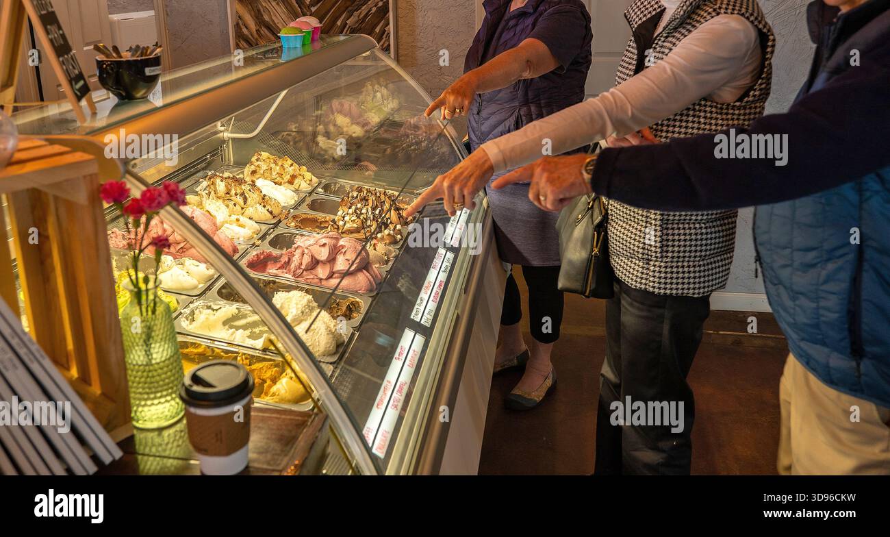 Le mani indicano la scelta preferita tra una varietà di deliziosi gelati congelati nella vetrina coperta di un negozio. Foto Stock