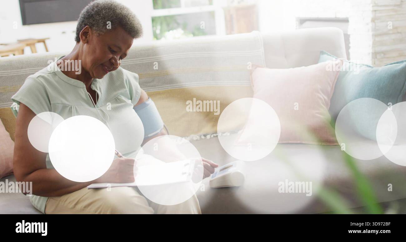 Registrazione di una donna in una blusa verde pallido con bracciale sul divano di casa, osservando la lettura del monitor Foto Stock