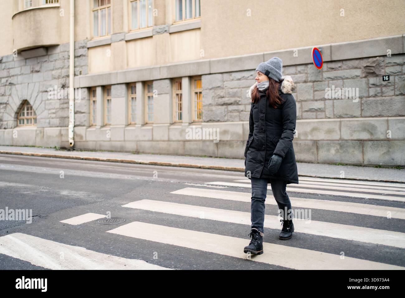 D'inverno, attraversate la strada a piedi. Donna in città sul crosswalk, zebra crossing. Giacca o cappotto. Foto Stock