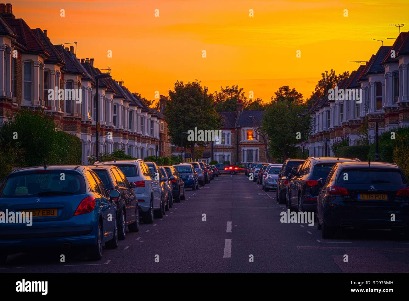 Londra, Regno Unito - 14 settembre 2025 - tramonto in una strada di case a schiera con auto parcheggiate nella baia residente intorno a West Hampstead Foto Stock