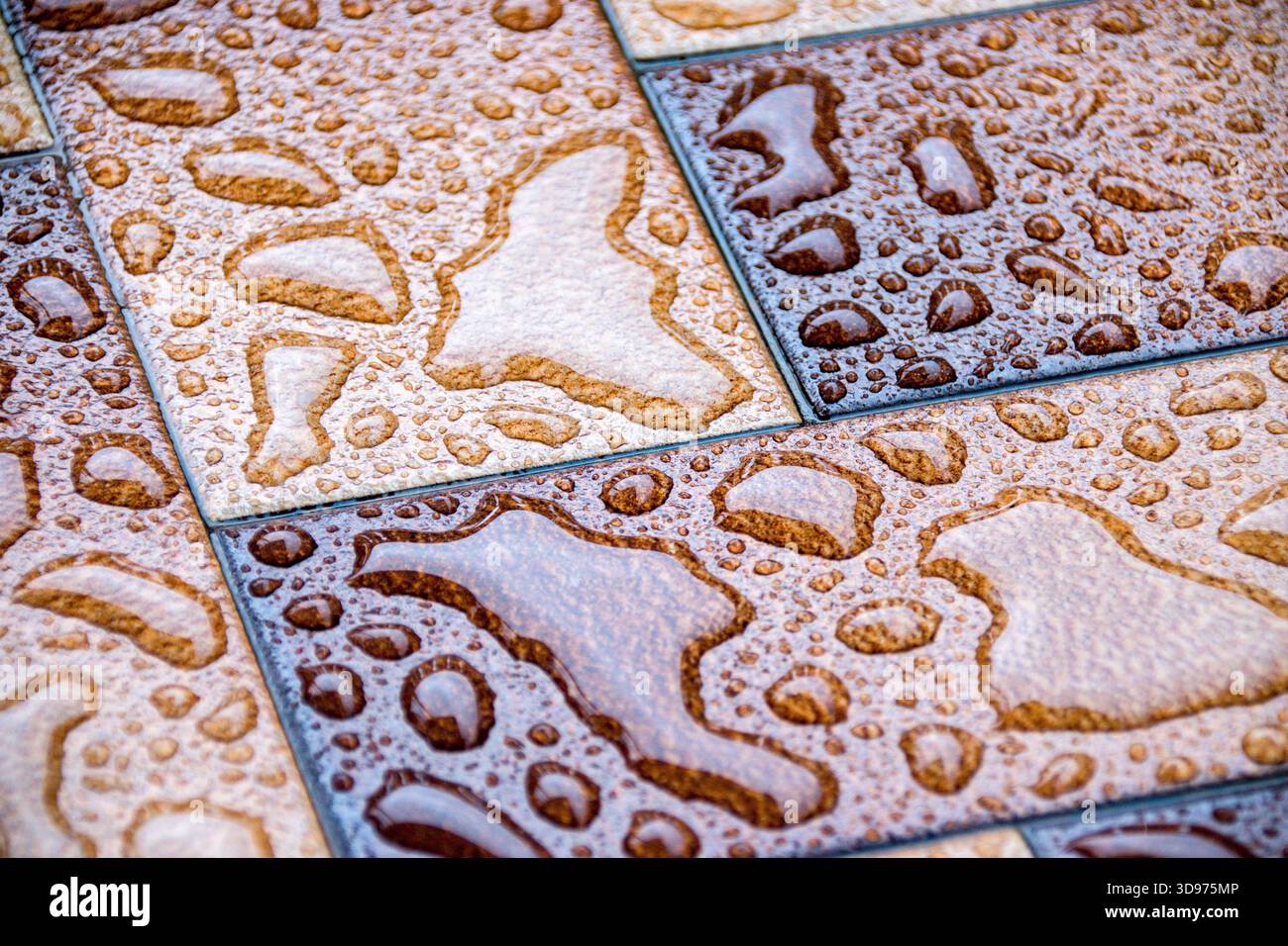 Spruzzi d'acqua sulle piastrelle, primo piano, messa a fuoco selettiva, acqua sul pavimento, sfondo astratto. Foto Stock
