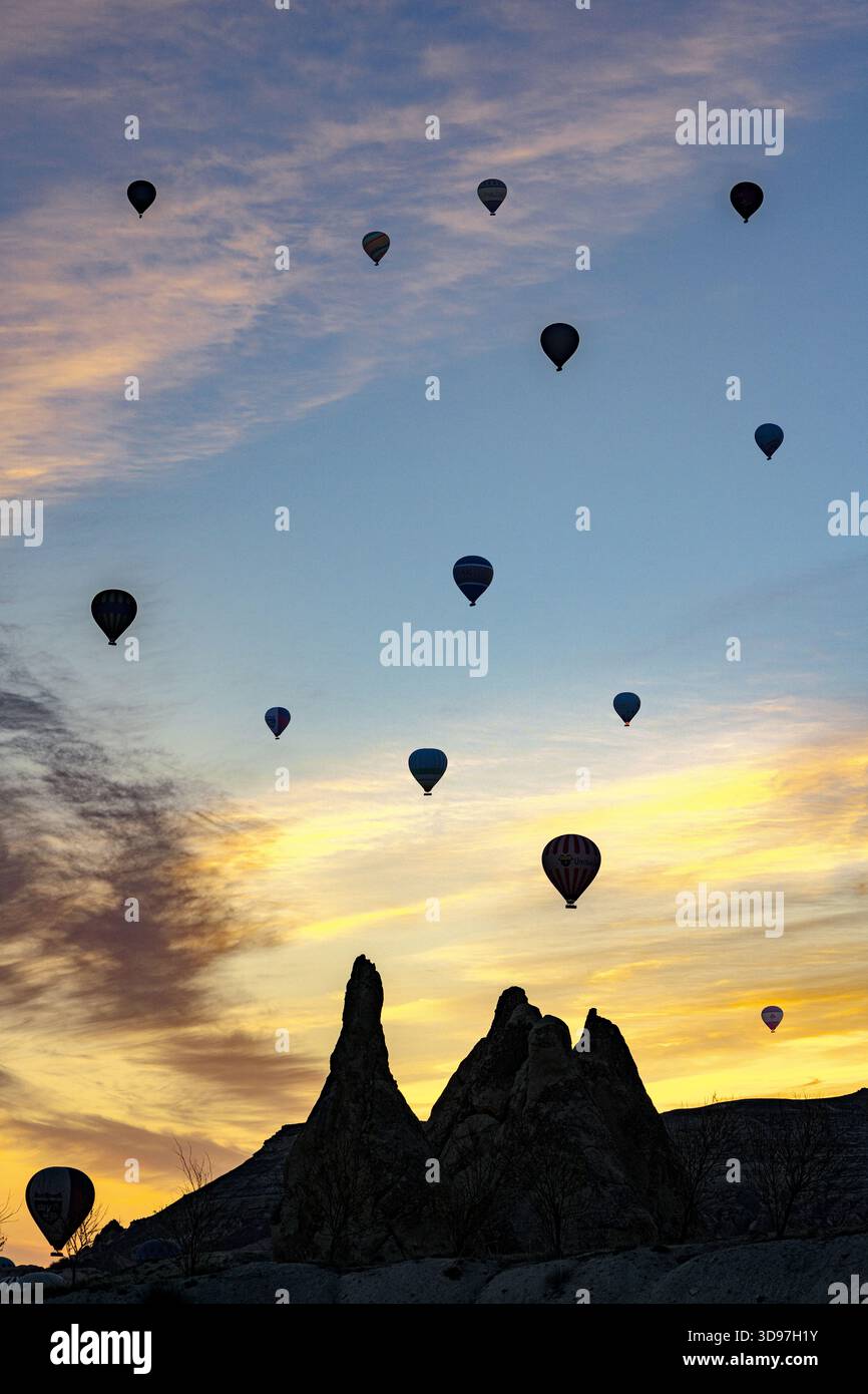 Vista delle mongolfiere che fluttuano serenamente all'alba su uno sfondo di cieli e formazioni rocciose dai colori vivaci, Love Valley, Cappadocia, Turchia. Foto Stock