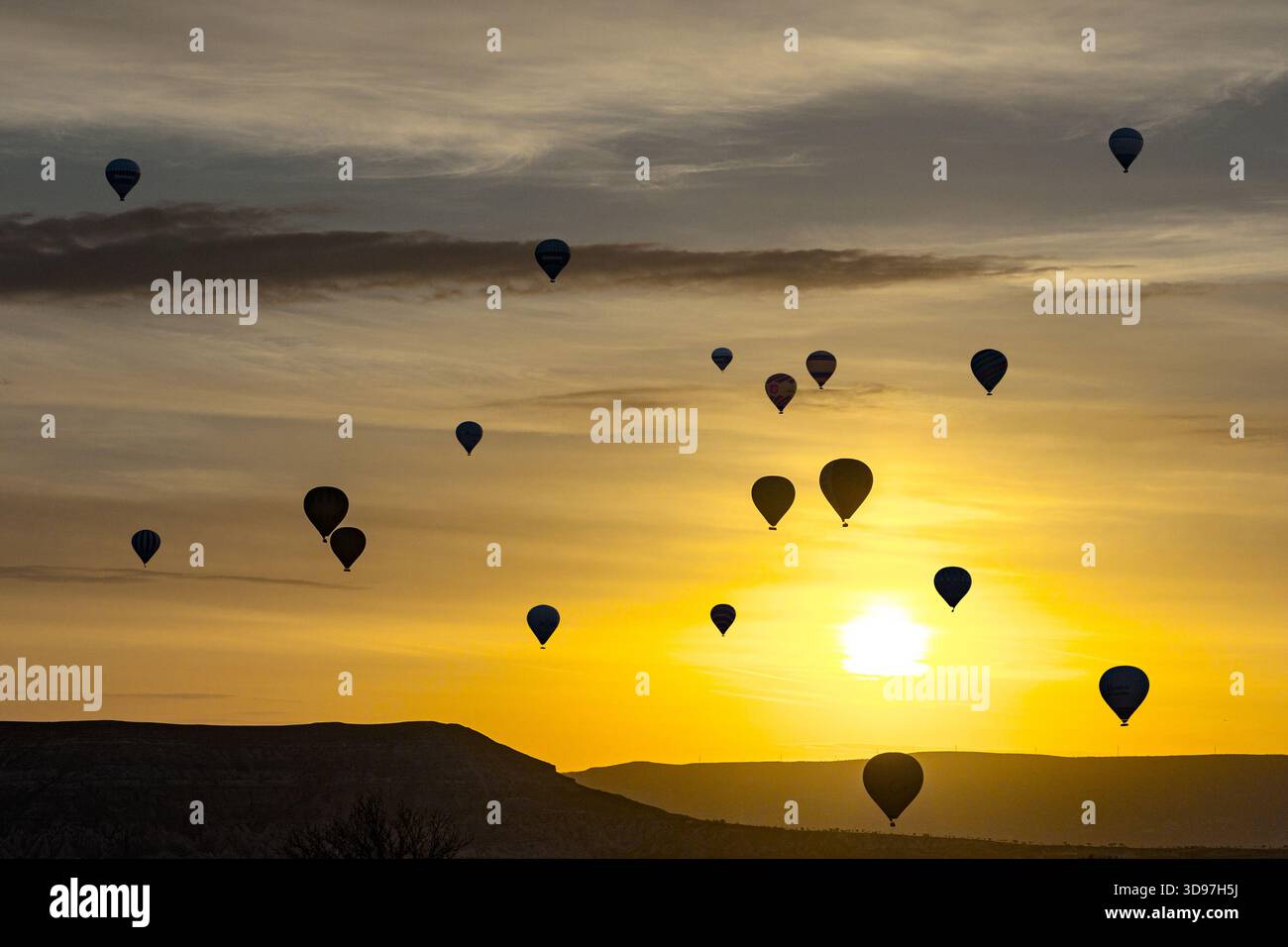 Vista aerea delle mongolfiere che si stagliano contro la vibrante alba dorata, dipingendo il cielo con sfumature di arancione e giallo, Goreme, Cappadocia, Foto Stock