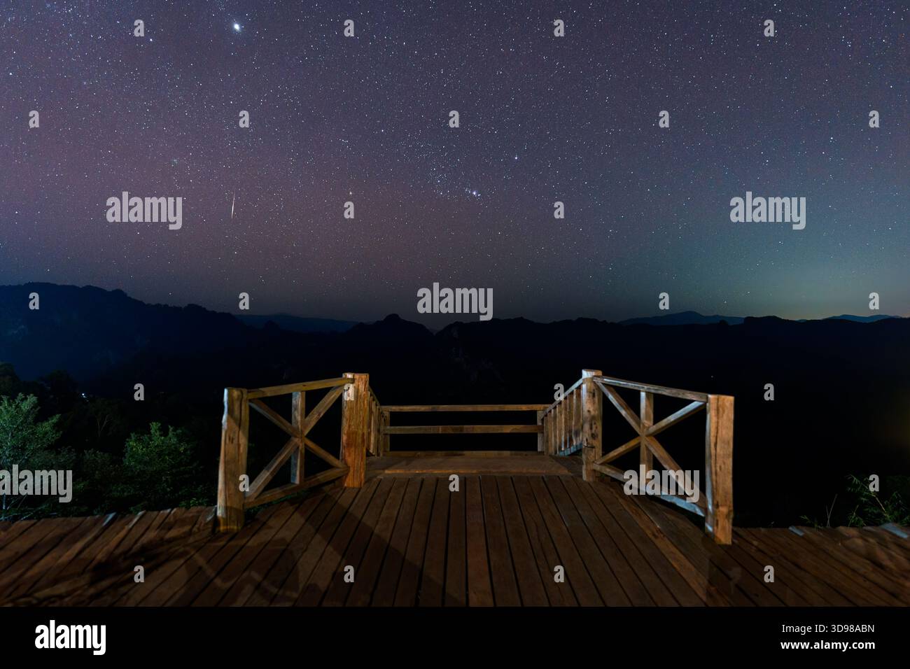 Bellissimo cielo stellato notturno con stella cadente su una terrazza in legno e una montagna a Ban Jabo, Thailandia Foto Stock