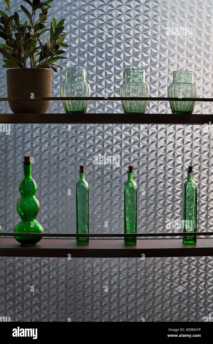 Elegante disposizione di bottiglie decorative su ripiani moderni con sfondo smerigliato Foto Stock