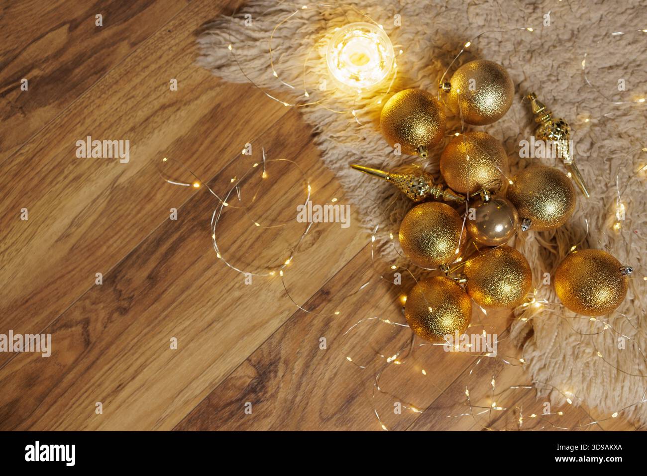 Vista dall'alto delle baule natalizie dorate e delle luccicanti luci delle fate sul pavimento in legno con soffice tappeto e spazio per le copie per il design delle feste. Foto Stock