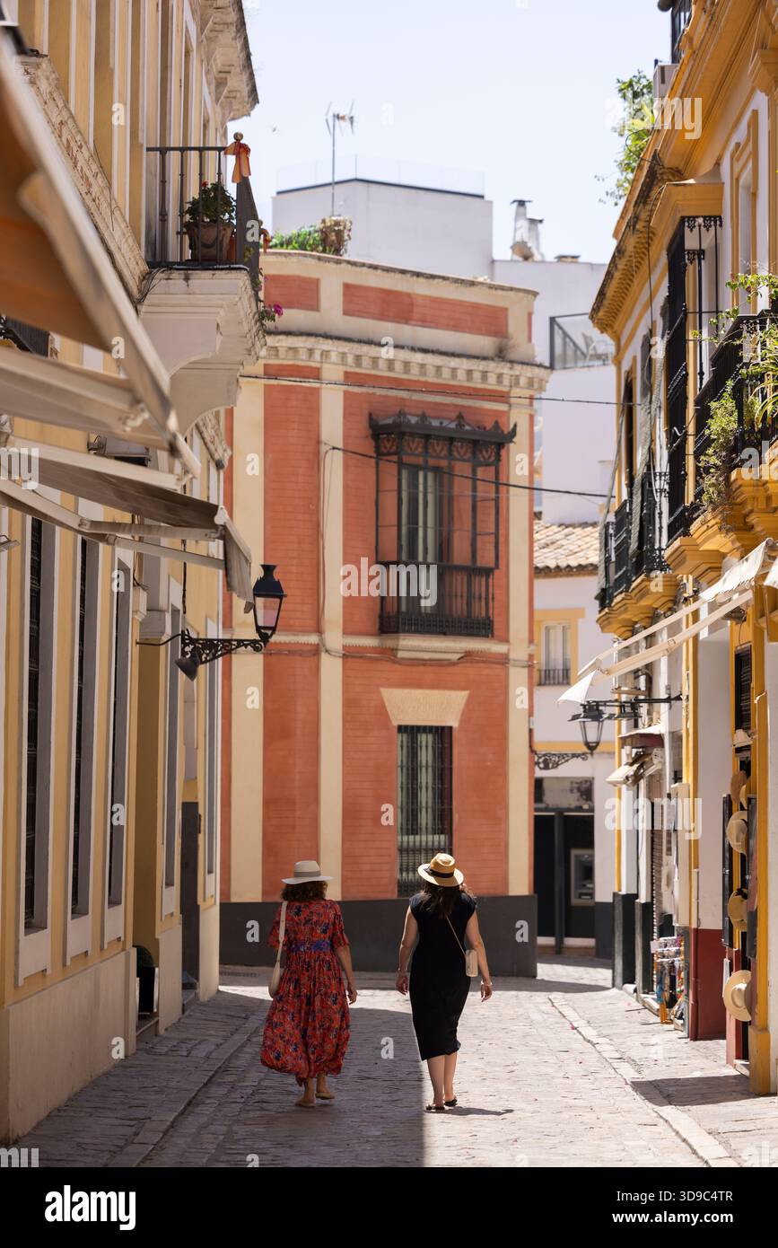 La gente cammina lungo le strade dense del quartiere Santa Cruz di Siviglia, Andalusia, Spagna. Foto Stock