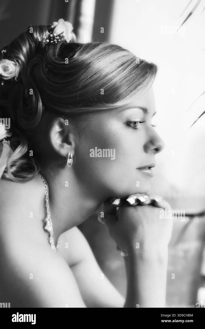 La bella sposa triste guarda in una finestra. bianco e nero Foto Stock