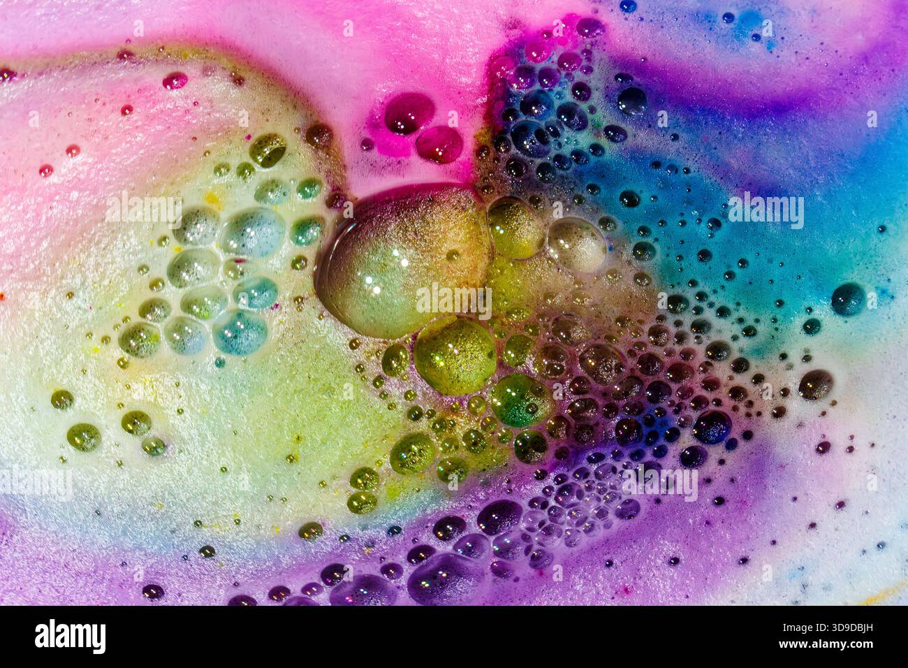 Colorato macro astratto di bolle vorticose e schiuma in tonalità rosa, blu, verde e giallo. Foto Stock