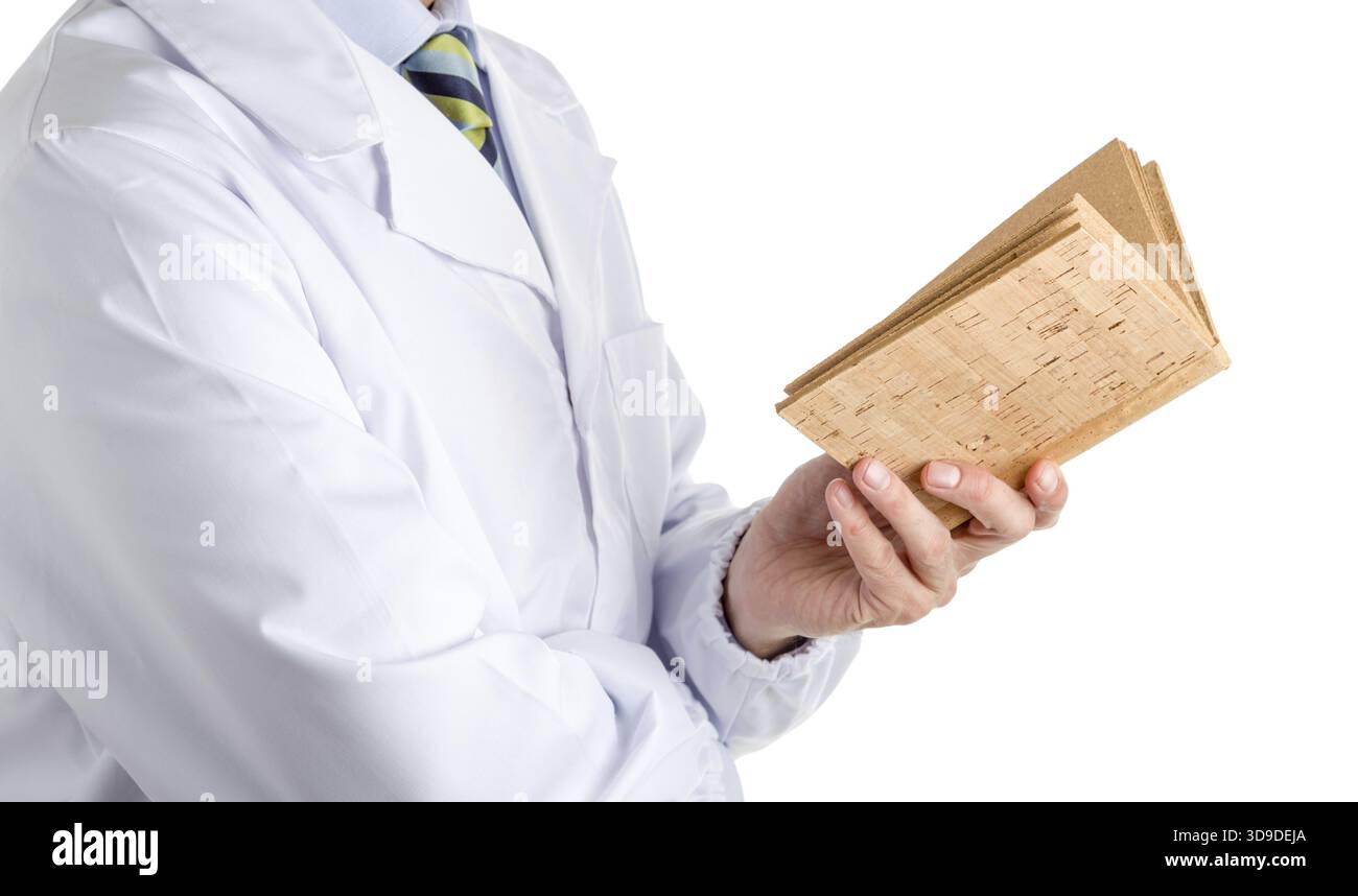 L'uomo vestito con cappotto medico bianco, camicia azzurro e cravatta reggimental lucida con le strisce blu scuro, blu chiaro e verde, sta leggendo un sughero bianco Foto Stock