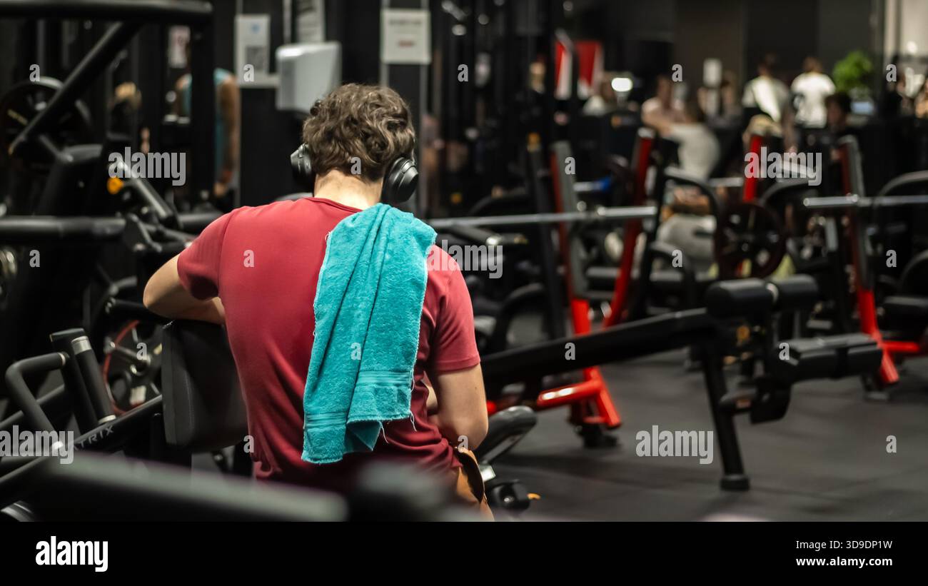 Lubiana, Slovenia 10 novembre 2025 uomo riposato con un asciugamano sulle attrezzature da palestra nel centro fitness Foto Stock