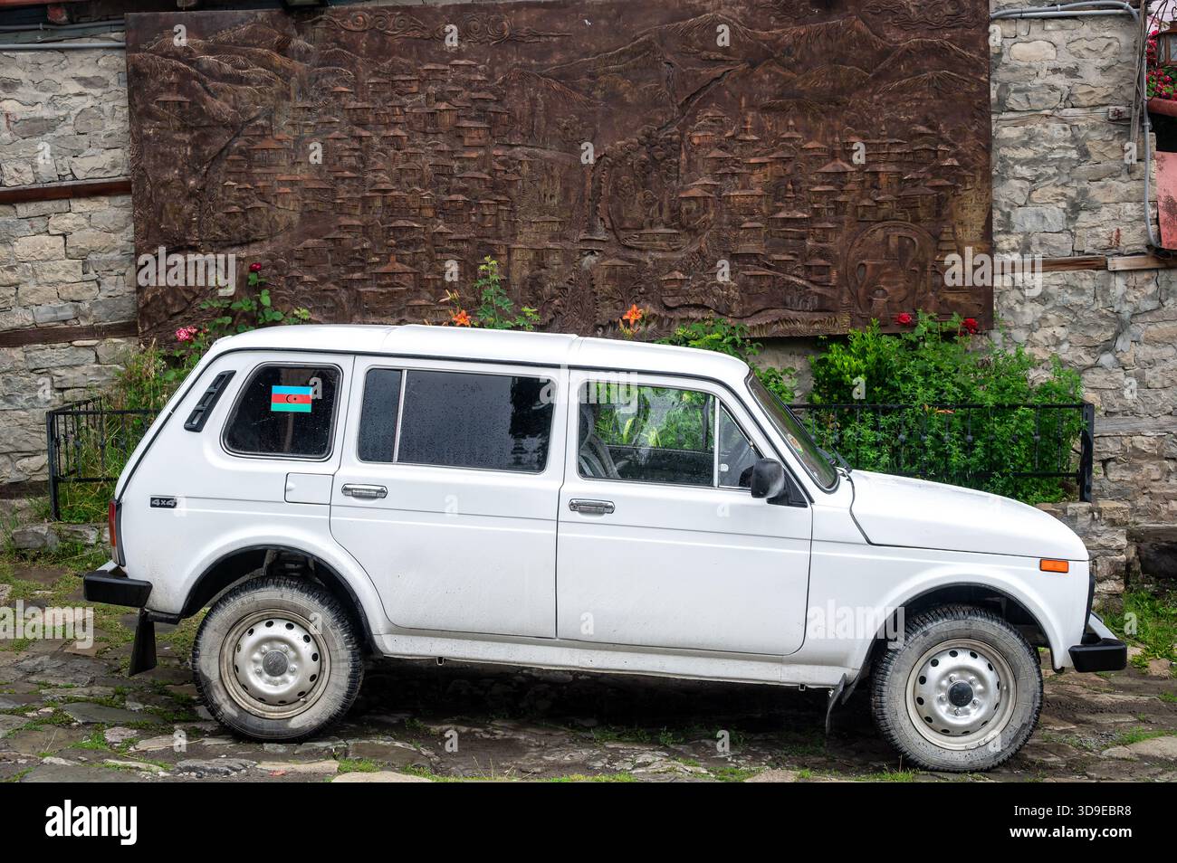 LAHIJ, AZERBAIGIAN - 17 GIUGNO 2025: Auto bianca Lada parcheggiata accanto a una mappa illustrata della città a Lahij, Azerbaigian. Foto Stock