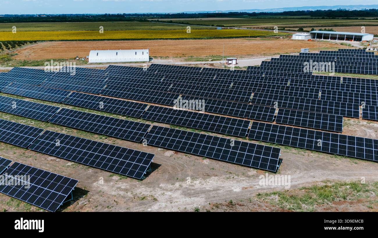 La vista aerea dei pannelli solari si estende attraverso il paesaggio, contrastando con i campi dorati e gli edifici distanti, Belgrado, la città di Belgrado, SER Foto Stock
