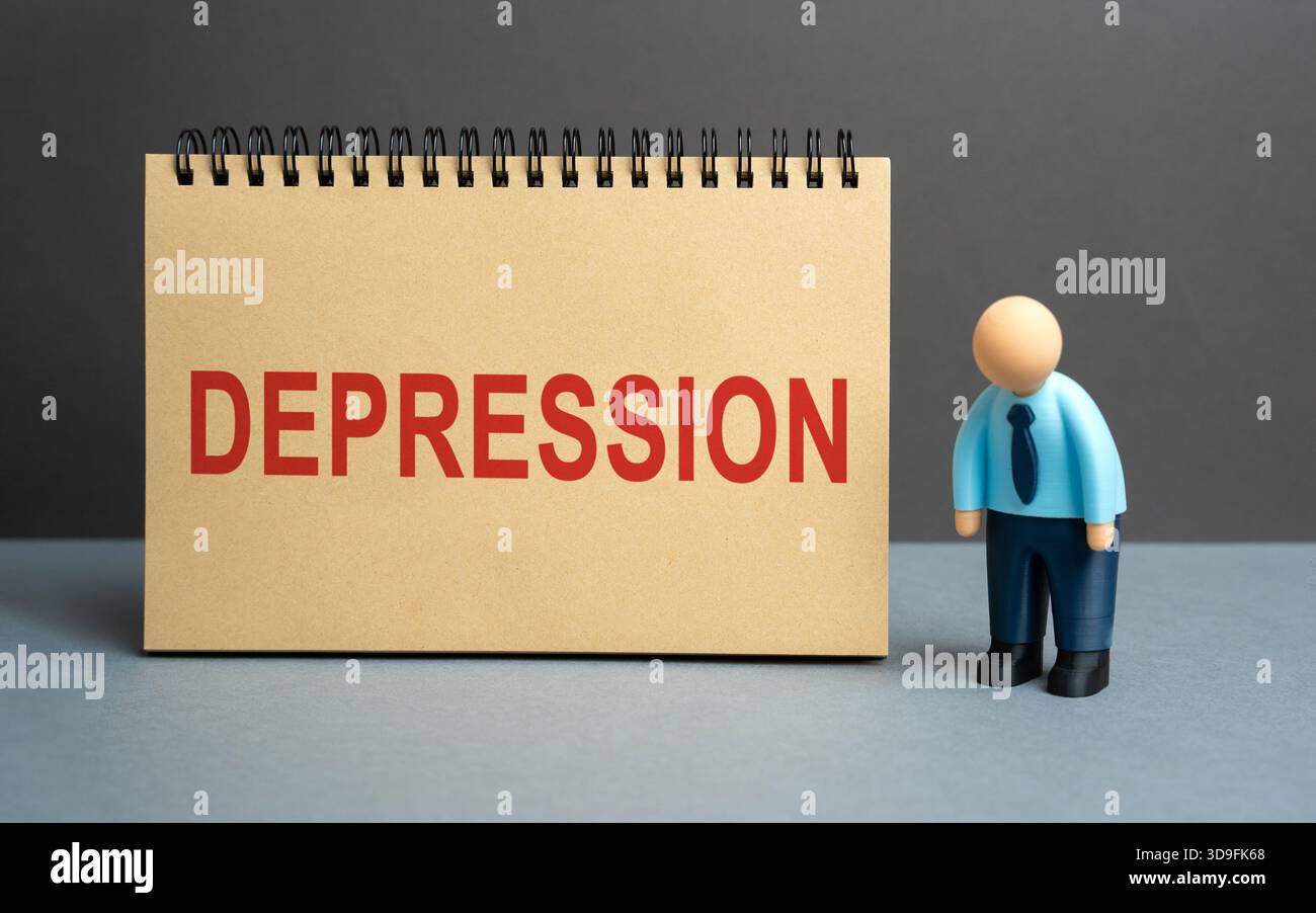 Un uomo d'affari stanco si trova vicino a un taccuino con la parola depressione. Simboleggiando problemi di salute mentale, stress, burnout, ed esaurimento emotivo sul lavoro Foto Stock