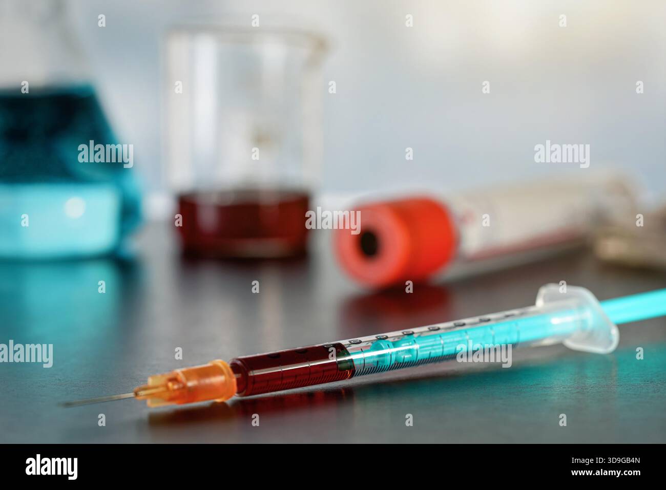 Ago per siringa ipodermica riempito con sangue rosso scuro su tavolo nero, sfondo offuscato dell'apparecchiatura di laboratorio Foto Stock