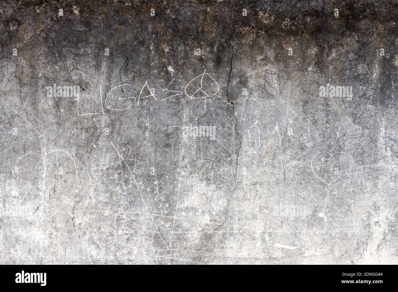 Gradiente orizzontale a contrasto elevato da scuro a luce su una parete di cemento graffiata pesantemente con un cartello di pace e testo sbiadito. Dispone di acque profonde Foto Stock