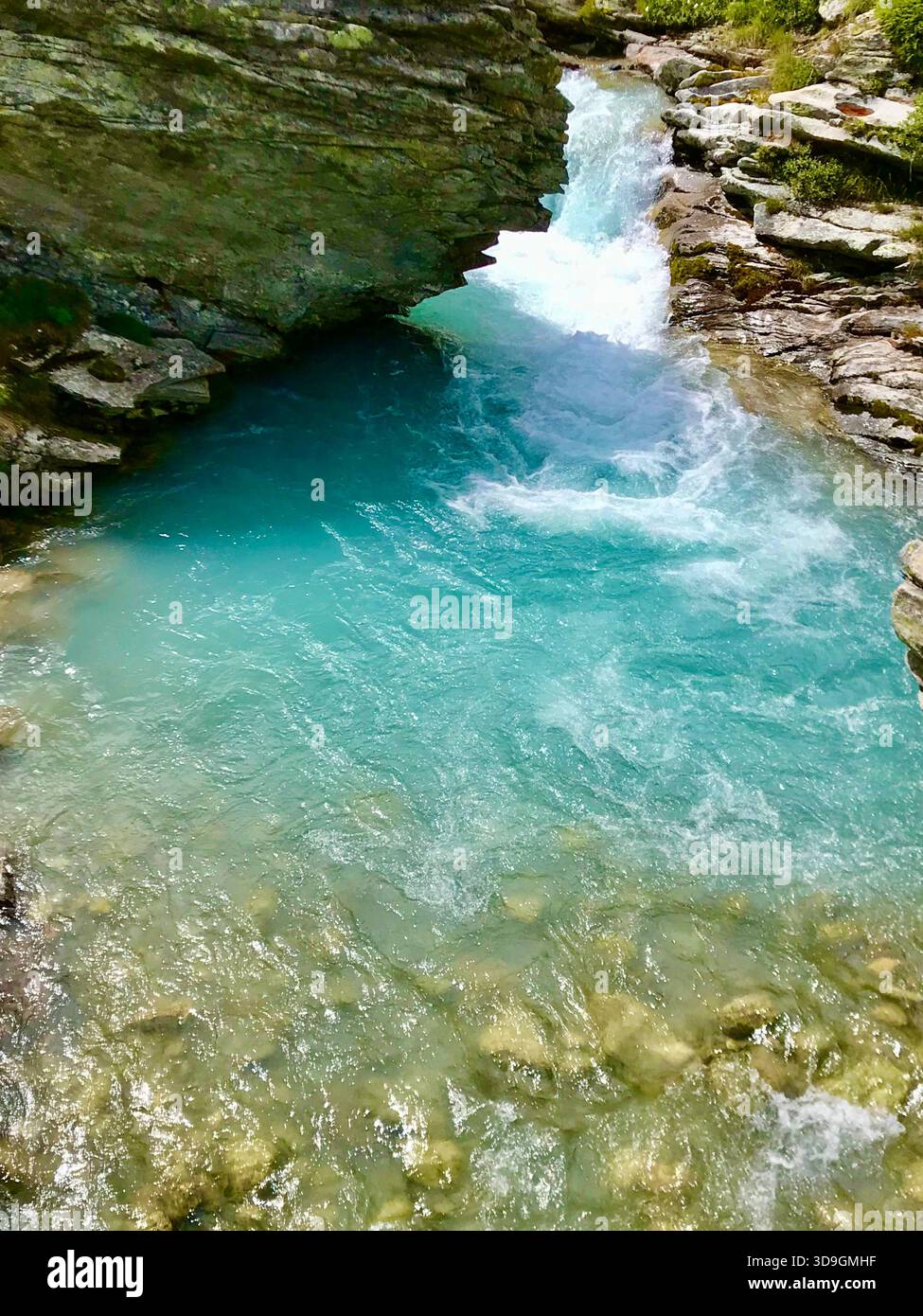 Un vivace torrente turchese scorre con potenza attraverso formazioni rocciose scure di ardesia vicino al bacino idrico di Mattmark sopra SaaS-Fee, Vallese, Svizzera Foto Stock