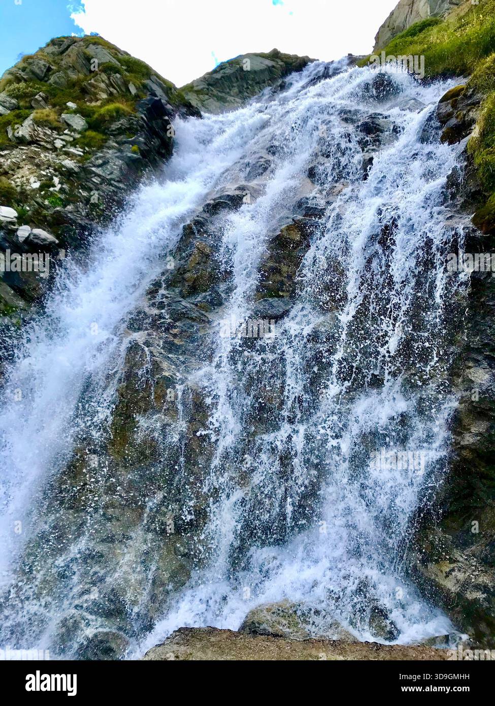 Il dinamico torrente di montagna scorre come una piccola cascata lungo un'imponente parete rocciosa presso il bacino idrico di Mattmark sopra SaaS-Fee, Vallese, Svizzera Foto Stock