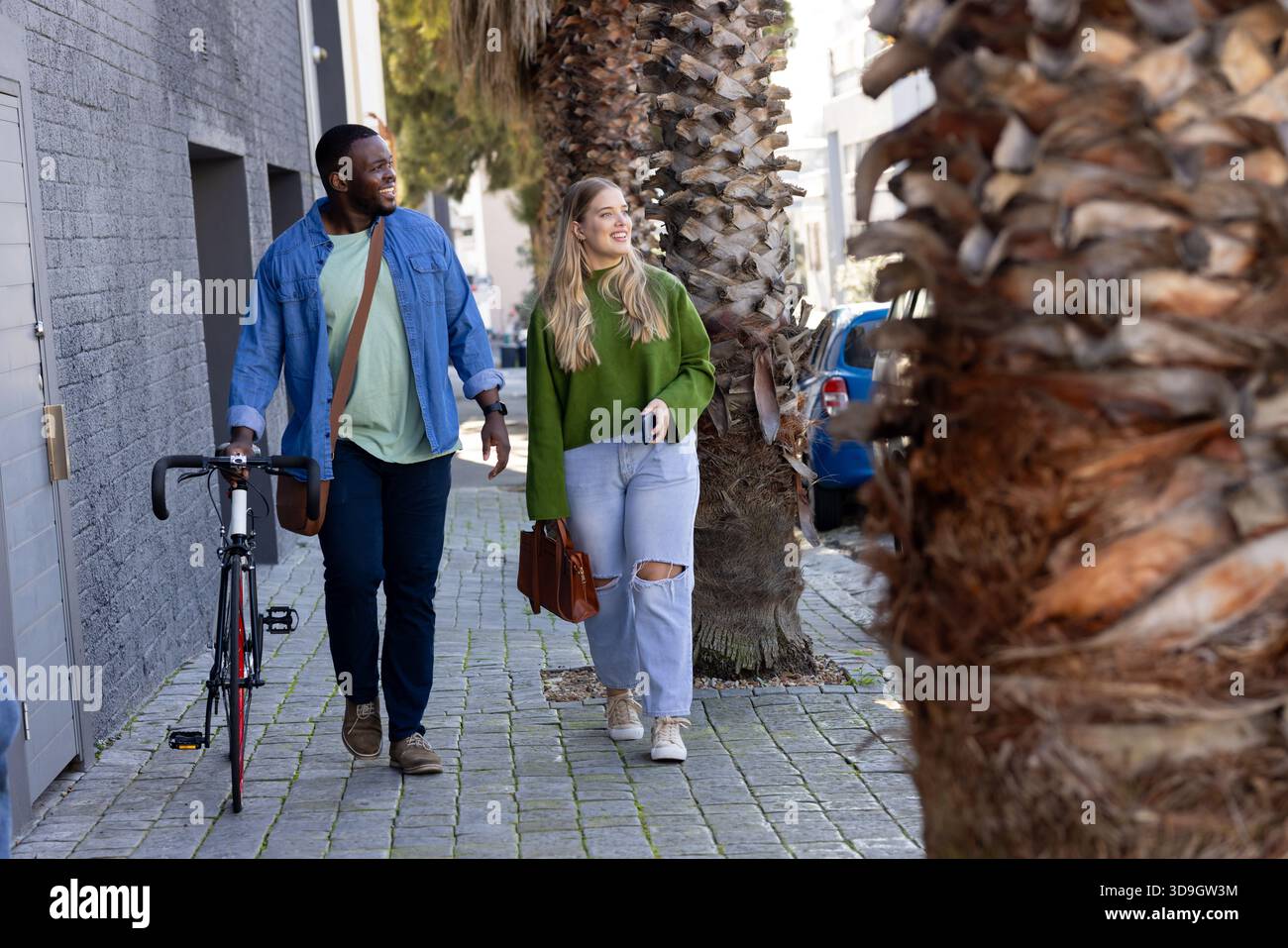 Diverse coppie che guidano la bicicletta su strada acciottolata indossando la borsa a tracolla e tenendo la borsa e lo smartphone Foto Stock