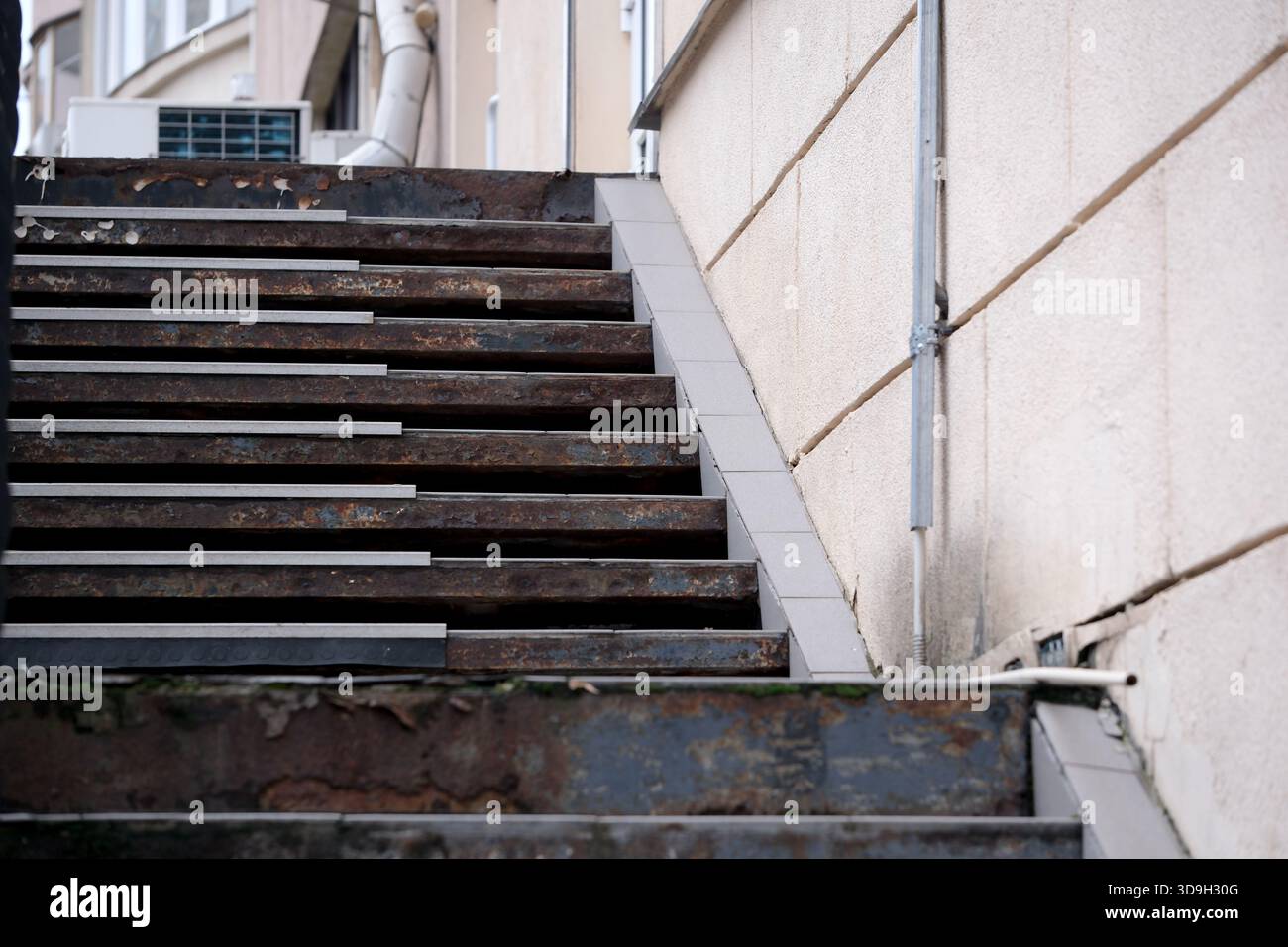 Le scale in metallo pesante mostrano segni di usura e ruggine accanto a una facciata modesta. Foto Stock