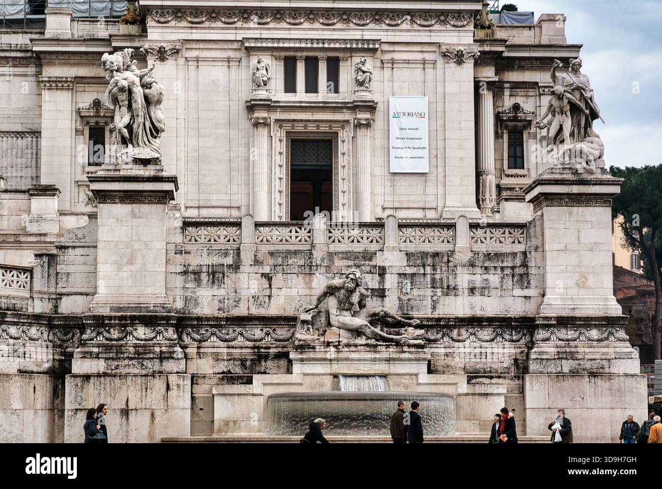 Vista dettagliata delle sculture allegoriche e della fontana al livello inferiore del Monumento Vittorio Emanuele II (Vittoriano), con una ba promozionale Foto Stock