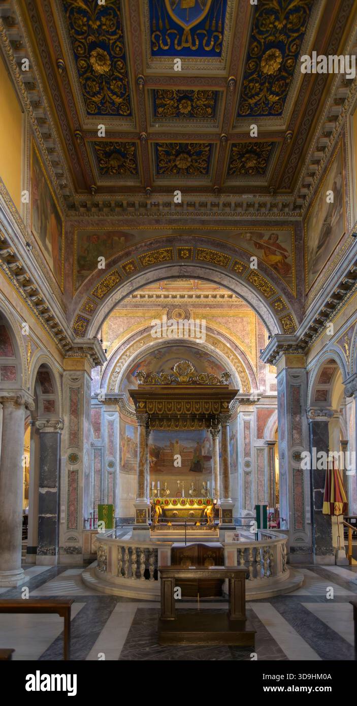 L'interno ornato di San Nicola in carcere a Roma, con un baldacchino sull'altare, archi affrescati e uno splendido soffitto a cassettoni dorati, Italia Foto Stock