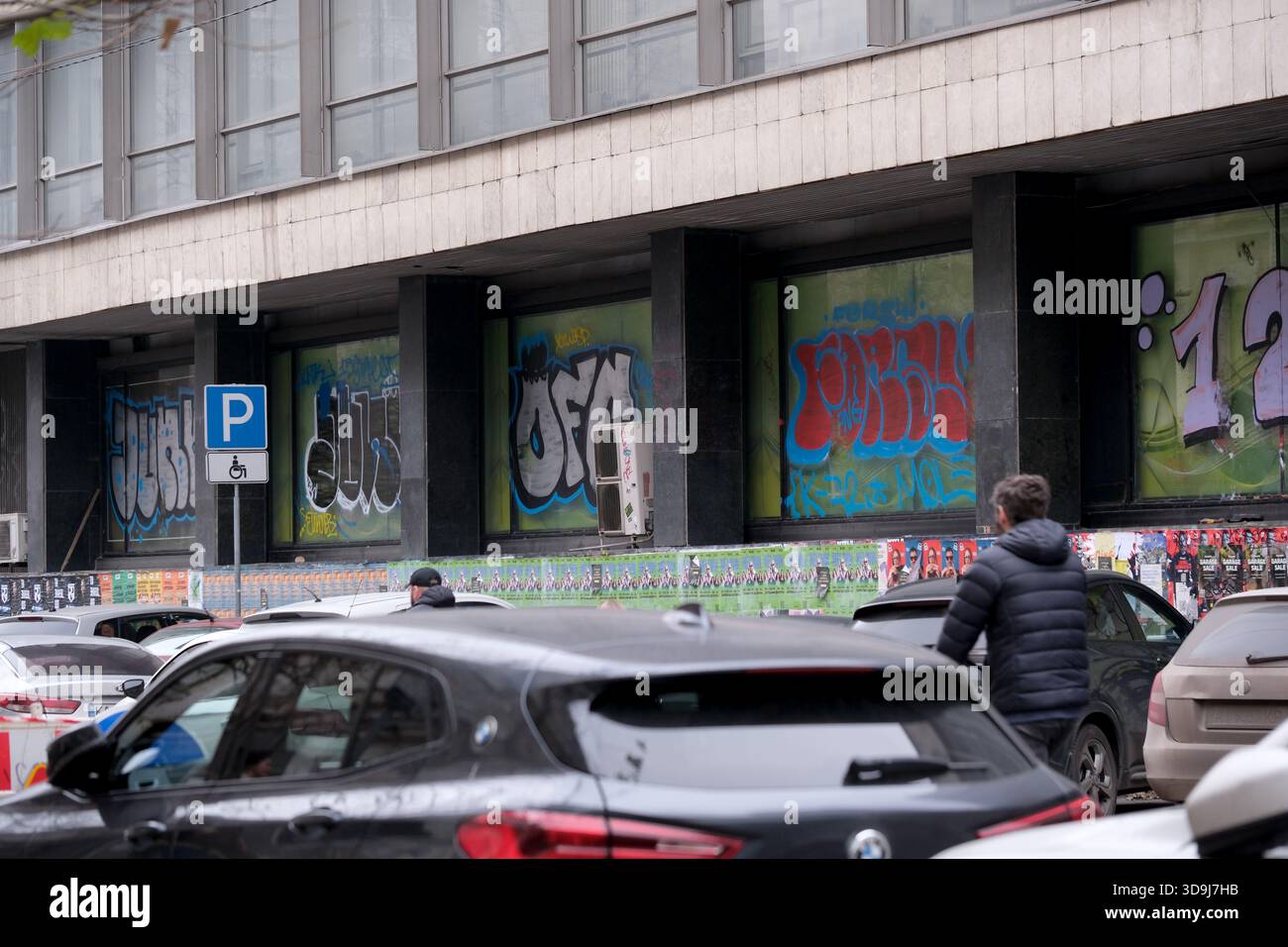Graffiti colorati coprono le pareti dell'edificio mentre la gente cammina lungo la strada. Kiev, Ucraina. 5 dicembre 2025. Foto Stock