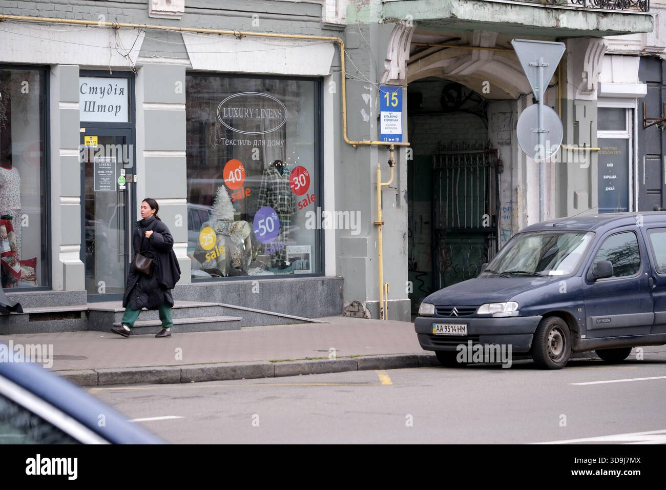 Una donna passeggia accanto a un negozio di abbigliamento che mostra colorati cartelli di vendita. Kiev, Ucraina. 5 dicembre 2025. Foto Stock