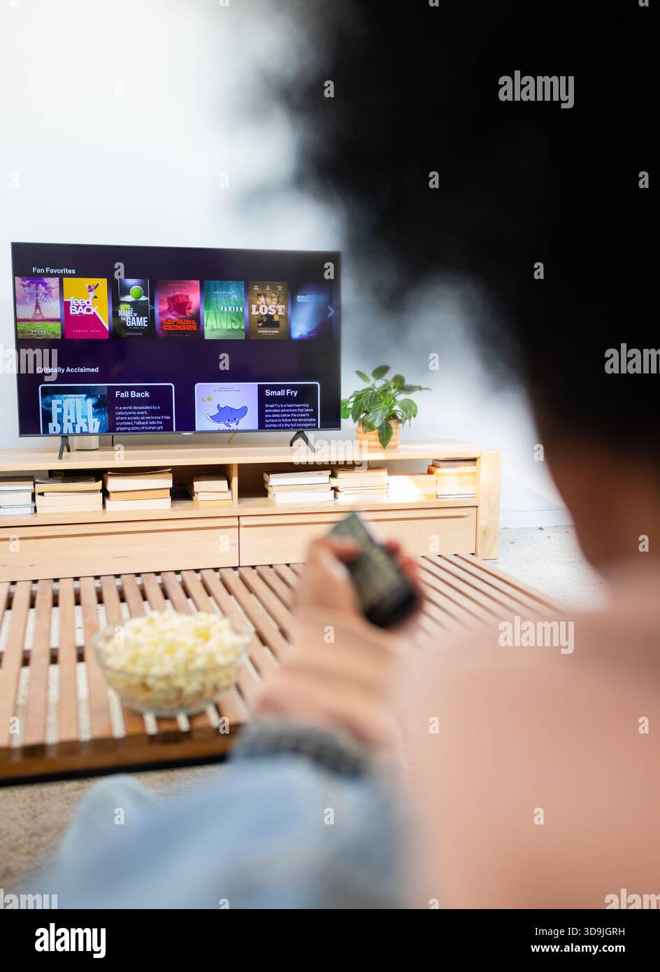 La TV a schermo piatto visualizza un menu in streaming mentre la ciotola di popcorn è appoggiata sul tavolino da caffè Foto Stock