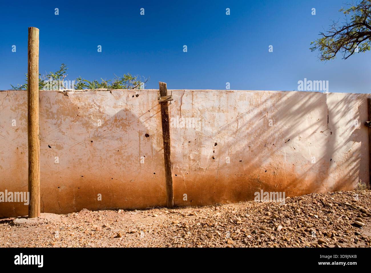 Una parete in adobe con agenti atmosferici contrasta il cielo azzurro liscio e luminoso sopra di essa Foto Stock