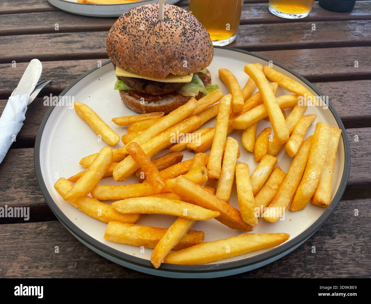Un pranzo informale all'aperto su un tavolo di legno con hamburger vegani, patatine fritte e birra. Wye Beach Hotel, Great Ocean Road, Australia - Immagine stock catturata con smartphone