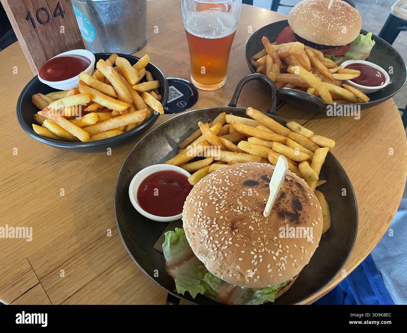 pranzo su un tavolo di legno con hamburger vegani, patatine fritte e birra. Aireys Pub, Australia - Immagine stock catturata con smartphone