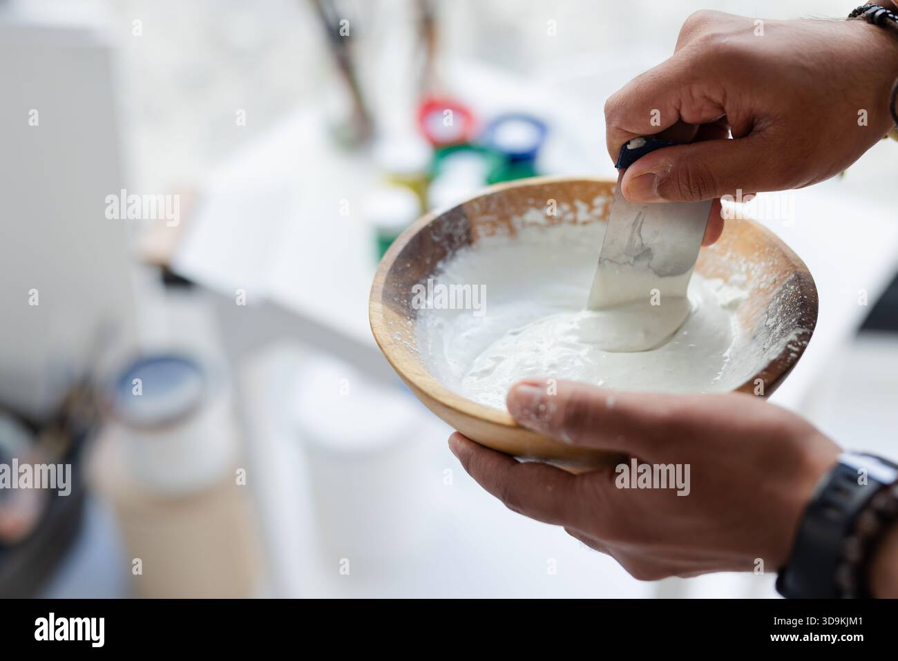 Pasta indiana per raschiare le mani di un uomo adulto utilizzando la spatola in una ciotola di legno presso lo studio d'arte, spazio copia Foto Stock