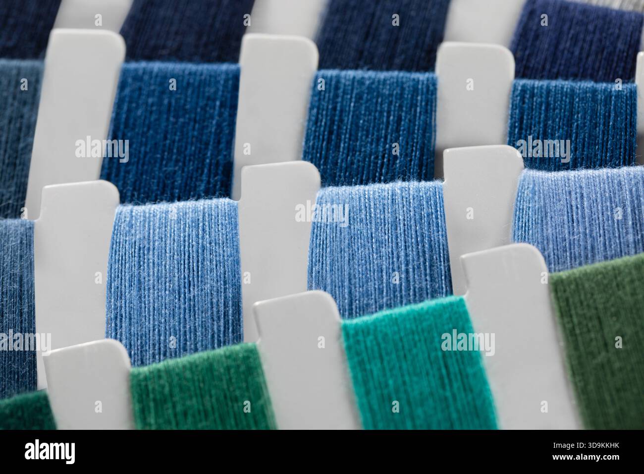 vista ravvicinata di campioni di filati di diversi colori come blu navy, blu scuro, blu chiaro e vari verdi. Foto Stock